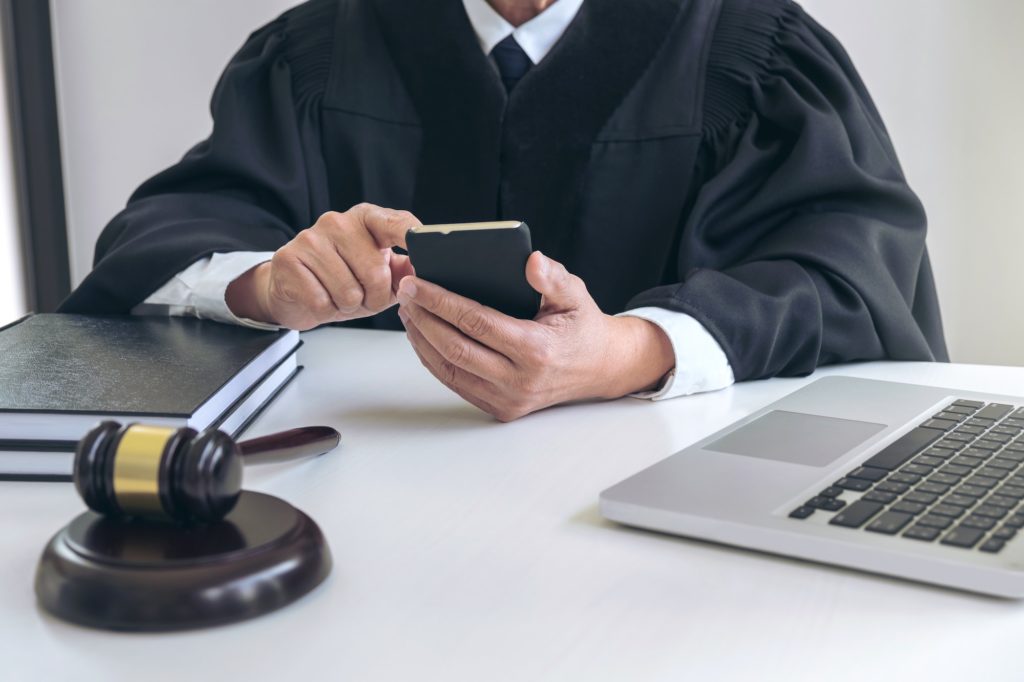 Male lawyer or judge working with smart phone and scales of justice